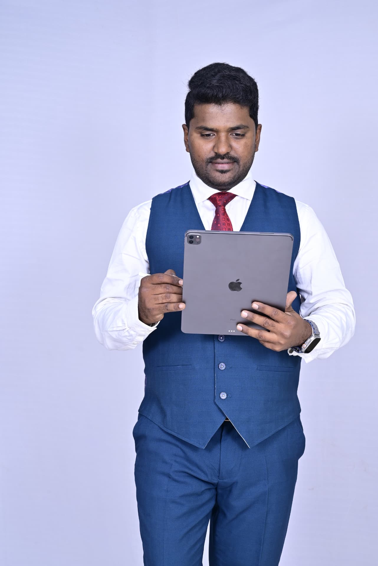 Dr. Ramesha A. reading on an iPad in a blue waistcoat